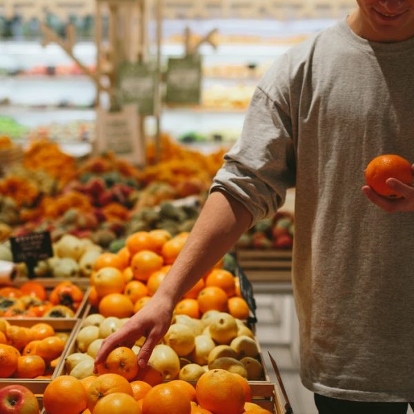 Man in produce aisle choosing citru fruits